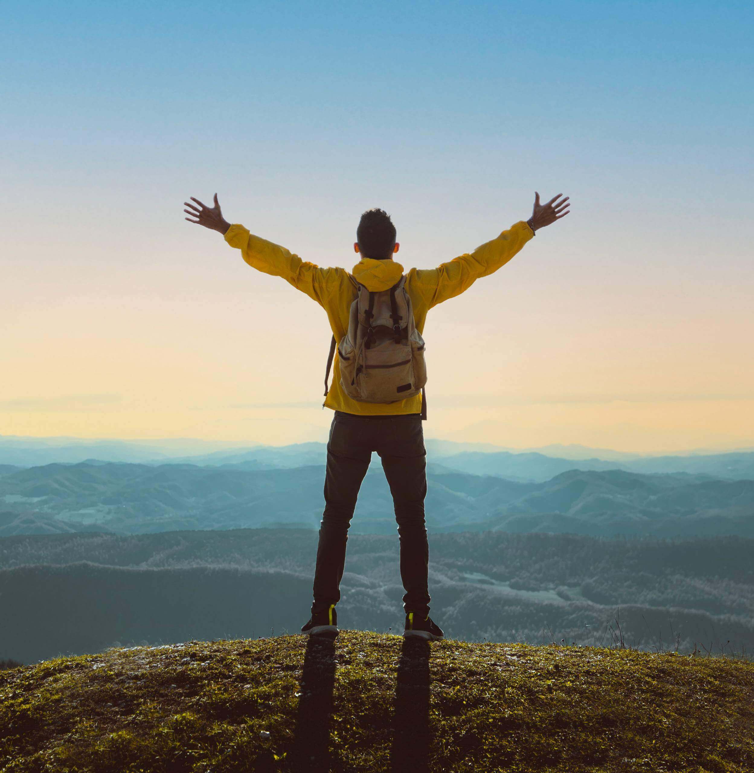Moving Minds Hypnotherapy - man spreading his arm to feel the breeze in the top of the mountain