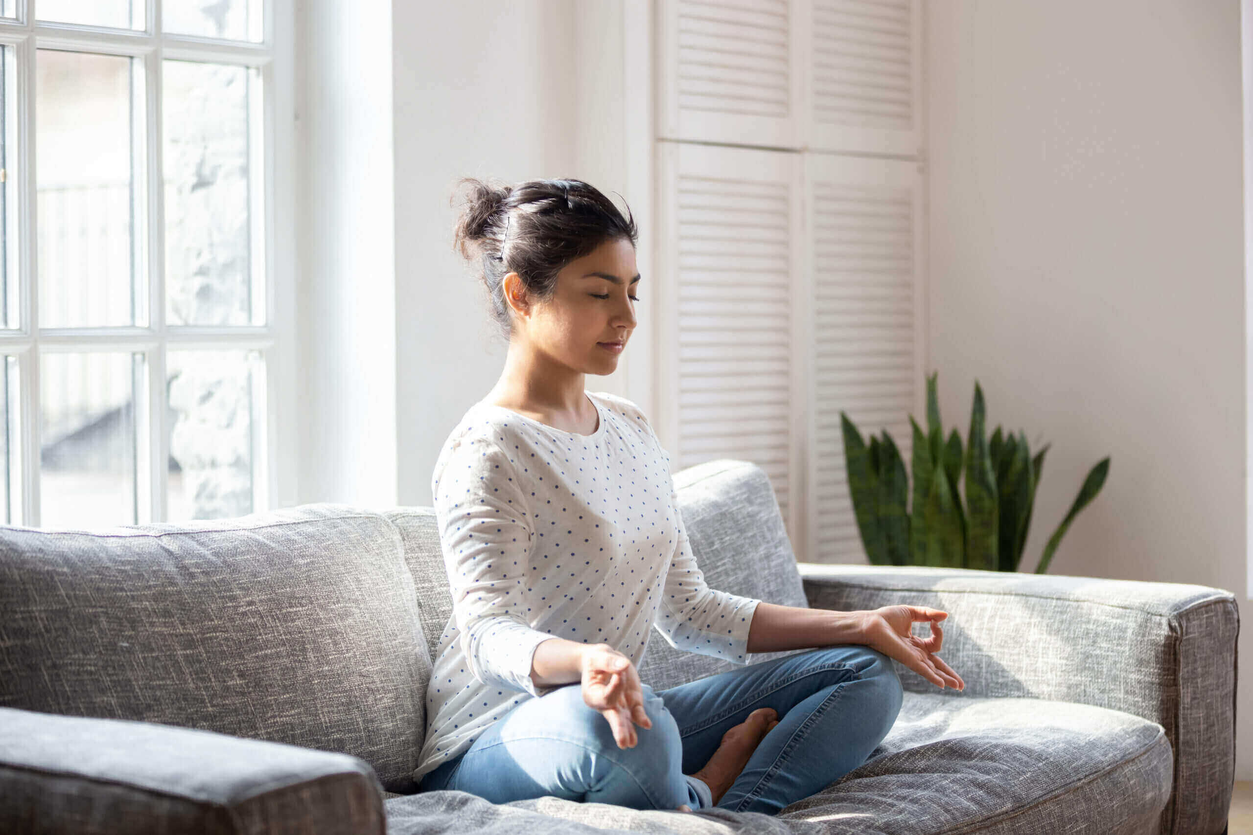 Moving Minds Hypnotherapy - Woman sitting on the couch meditating
