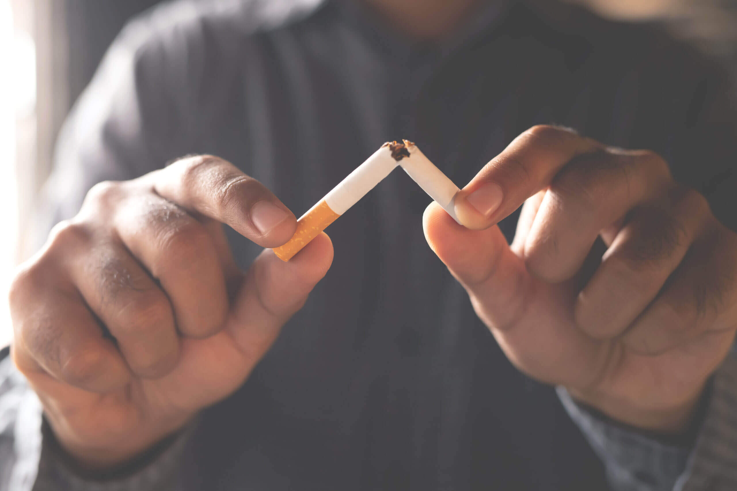 Moving Minds Hypnotherapy - a hand holding two sticks of cigarettes